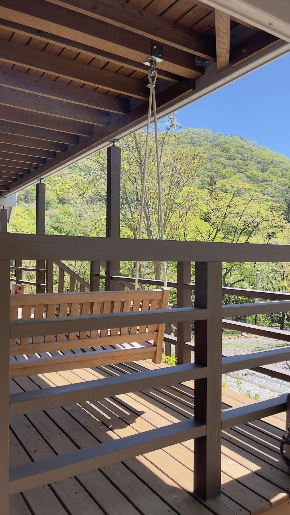 軒下のブランコと、その向こうに広がる緑。