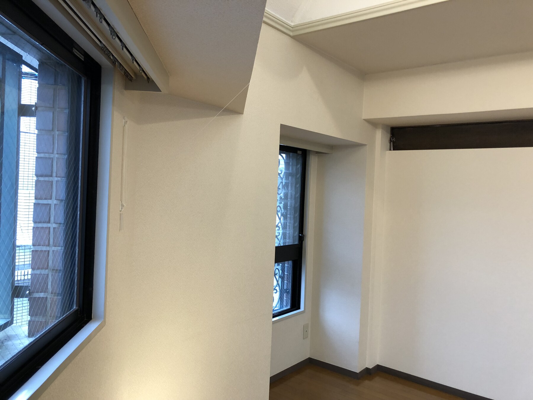 家具設置前の窓辺。二つの窓と梁、木の床が見える